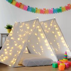 two tents with lights on them are sitting in the middle of a room next to toys