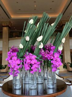 purple and white flowers are in vases on a table