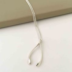 This stunning vintage inspired wishbone charm is a simple yet classic piece. Part of the signature Katie Mullally wishbone collection, the bespoke design is said to bring good luck to the wearer. The wishbone charm is worn with a 18 inch silver curb chain. As with all Katie Mullally designs, the charm is collectable and can be delicately layered with other pieces. The charms and chains are all solid sterling silver.Katie Mullally charms are handmade in the UK and hallmarked at The London Assay O Alphabet Jewelry, Wishbone Necklace, Mens Jewelry Bracelet, Bespoke Design, Heart Jewelry, Curb Chain, Cleaning Jewelry, Birthstone Jewelry, Inspirational Gifts