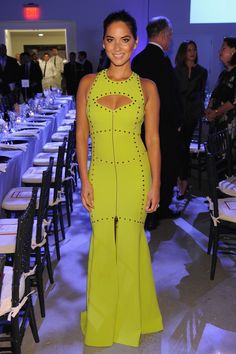 a woman in a bright green dress standing next to a table with white tables and chairs