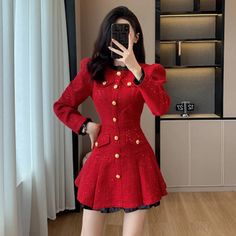 a woman taking a selfie wearing a red coat and black skirt with gold buttons