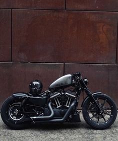 a black motorcycle parked in front of a brown wall