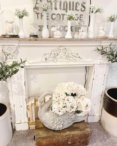 a white fireplace mantel with vases and flowers on it