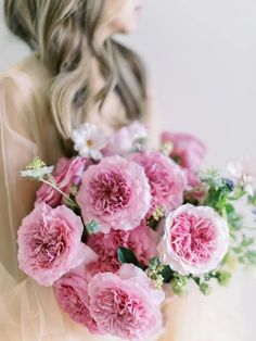 a woman holding a bouquet of pink flowers