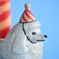 a white poodle figurine wearing a party hat