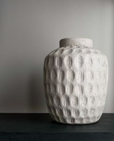 a white vase sitting on top of a wooden table