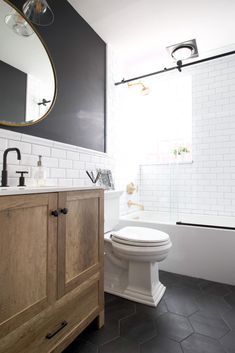 a white toilet sitting next to a wooden cabinet in a bathroom under a large mirror