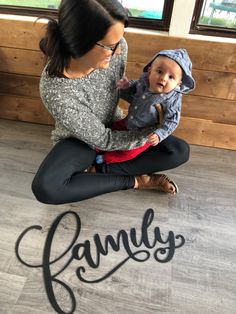 a woman sitting on the floor holding a baby in her lap with the word family written across it