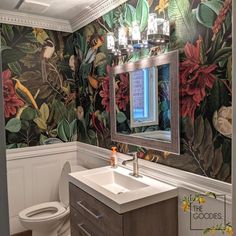 a bathroom with floral wallpaper and a mirror above the sink, along with a toilet