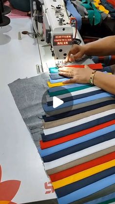 a woman is using a sewing machine to sew on colorful fabrics in a factory