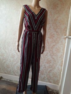 "Striped jumpsuit in red\\white and brown stripes,  a deep V at the front and back and a tie belt.  Very easy to wear, wide palazzo legs' Bust;  40\" Waist;  32\" Inside leg;  27\" Width at ankle;  11\"   Made by OVS         syntheyic" Striped V-neck Jumpsuits And Rompers For Summer, Striped Sleeveless Jumpsuits And Rompers For Spring, Striped Sleeveless Jumpsuit For Spring, Sleeveless Striped Jumpsuits And Rompers For Spring, Striped Jumpsuits And Rompers For Summer Workwear, Chic Striped Jumpsuits And Rompers For Summer, Chic Striped Summer Jumpsuits And Rompers, Elegant Striped Sleeveless Jumpsuits And Rompers, Striped Overalls Jumpsuits For Spring