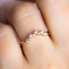 a woman's hand wearing a gold ring with three small white stones on it