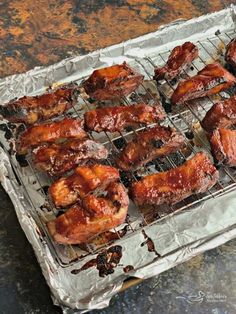 chicken wings are cooking on the grill in tin foil, ready to be grilled