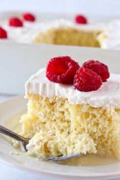 a piece of cake with white frosting and raspberries on top