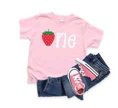 Strawberry One Birthday Shirt Shirt shown on a white or light pink shirt.  Jeans not included.   PLEASE NOTE, I DO NOT HAVE CONTROL OVER THE PACKAGES ONCE THEY LEAVE MY SHOP. ALL SHIPPING IS WITH THE UNITED STATES POSTAL SERVICE FIRST CLASS MAIL UNLESS AN UPGRADE IS PURCHASED, THEN IT IS PRIORITY MAIL. USPS HAS FULL CONTROL OF DELIVERY ONCE IT LEAVES ME! All clothing orders are a three - five business day production time with out the rush order that you can purchase below.  If you have any questions, please feel free to message me.   If you need your order shipping more quickly, please add this link: https://www.etsy.com/listing/454845998/rush-my-order?ref=shop_home_active_1 See my other listings at: https://www.etsy.com/shop/purpleaspenkids?ref=hdr_shop_menu One Birthday Shirt, One Year Old Birthday, Light Pink Shirt, Strawberry Birthday, 1st Birthday Shirts, First Birthday Shirts, 1 Birthday, Birthday Tee, One Year Old