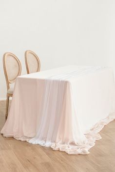 a table with two chairs and a white table cloth on top of it in an empty room