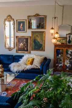 a living room with blue couches and pictures on the wall above them, along with potted plants