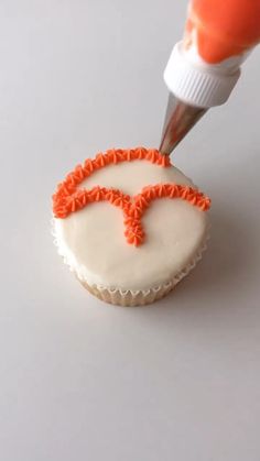 a cupcake being decorated with orange icing