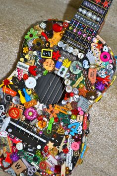 a guitar covered in buttons and magnets sitting on the floor next to a carpet