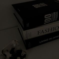 two books sitting on top of each other next to a piece of paper with the word fashion printed on it