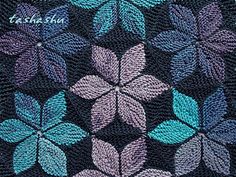 a crocheted blanket with blue and purple leaves on it's side, in the shape of a flower