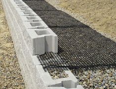 cement blocks are placed on the side of a concrete wall with gravel in between them