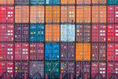 the cargo containers are stacked on top of each other in different colors and sizes,