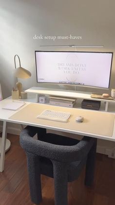 a desk with a computer on it and a chair in front of the monitor that is turned on