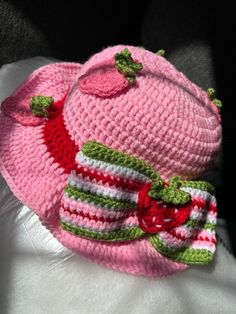 a crocheted pink hat with green trim