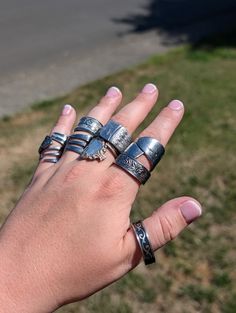 a person's hand with five different rings on it, and one is holding the other