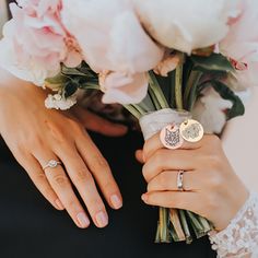 two hands holding a bouquet of flowers and wedding rings on their fingers, with the bride's ring resting on her finger