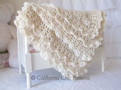 a white crocheted blanket sitting on top of a wooden chair next to teddy bears