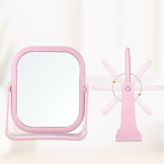 there is a pink mirror and stand on the table