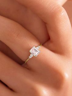 a woman's hand with a diamond ring on her left hand and an emerald stone in the middle