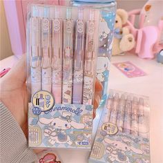 a person holding up a set of hello kitty pens in a box with other items