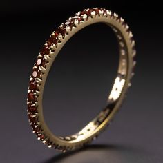 Why we love it: This garnet band has a classic design with rich red garnets continuing all the way around the band! It is a great choice for a wedding band or a stand alone piece. Highlights: - 0.70 carat of natural garnets - Full eternity design - Solid 14k yellow gold setting Dimensions: The ring measures 1.9mm across (north south) and 2.0mm from finger to top Sizing: As an eternity ring, this can't be easily resized. It is only available in size 5.5, 6.5, and 8.0. Additional Notes: This is pa Luxury Stackable Ruby Ring For Wedding, Elegant Ruby Eternity Band In Yellow Gold, Elegant Yellow Gold Ruby Eternity Band, Elegant Red Eternity Band For Anniversary, Luxury Stackable Ruby Ring, Gold Ruby Eternity Band With Prong Setting, Ruby Eternity Band With Prong Setting For Formal Occasions, Formal Ruby Eternity Band With Prong Setting, Elegant Red Stackable Eternity Band