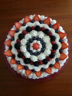 a cake decorated with strawberries, blueberries and blackberries