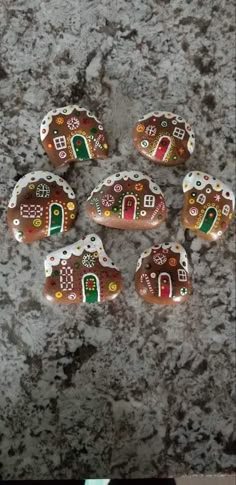 six gingerbread cookies with frosting and decorations on them sitting on a granite surface