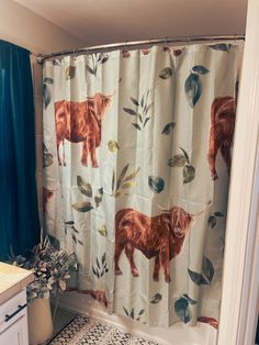 a shower curtain with an image of a cow and leaves on it in a bathroom