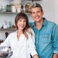 a man and woman standing in front of a counter holding a bowl with food on it