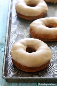 three glazed donuts sitting on top of a metal tray next to eachother