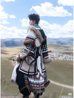 a man dressed in native clothing standing on top of a hill