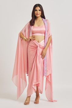 Pink satin draped dhoti skirt with front knot and asymmetric hem. Comes with padded bralette and  embroidered border satin cape.
Components: 3
Pattern: Embroidered
Type Of Work: Sequins, Glass Beads
Neckline: Bralette: Scoop
Sleeve Type: Cape: Draped Slit
Fabric: Satin
Color: Pink
Other Details: 
Tassel edged cape
Attached lining
Product weight: 1 kg
Occasion: Mehendi and Haldi - Aza Fashions Cape Dress Outfit, Dhoti Style Dresses, Dhoti Skirt, Cape Women, Cape For Women, Indian Bridesmaid Dresses, Satin Bralette, Sangeet Outfit, Shrug For Dresses