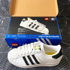 a white adidas sneaker with black and yellow stripes next to a blue box