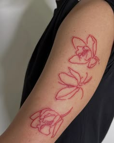 a woman's arm with red ink on it that has flowers drawn on it