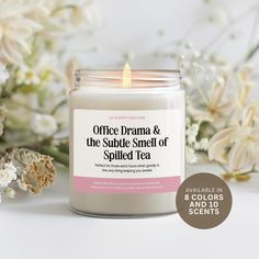 the candle is next to some flowers on a white surface with text that reads office drama & the subtle smell of spirited tea