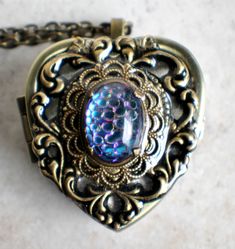 "Heart music box pendant. This heart shaped music box is inspired by the gorgeous music box pendants of era's gone by. Music box is pill box size, please look at the dimensions for exact size. A heart shaped locket has been adorned with a bronze stamping of a lacey edged floral heart with a elegant bronze filigree setting holding a gorgeous German helio scale back mosaic glass cabochon. The cabochon changes four different color as it is moved and the light hits it. The lacey edged floral heart a Vintage Brass Heart-shaped Jewelry, Vintage Brass Heart Shaped Jewelry, Vintage Heart-shaped Brass Jewelry, Collectible Medallion Jewelry For Valentine's Day, Heart-shaped Vintage Charm Jewelry For Keepsake, Vintage Charm Jewelry For Valentine's Day, Vintage Brass Heart Jewelry, Ornate Heart-shaped Jewelry With Intricate Design, Antique Heart-shaped Brass Jewelry