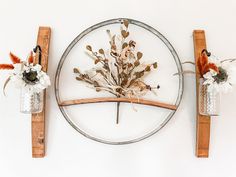 two vases with flowers are hanging on the wall next to each other in front of a circular metal frame