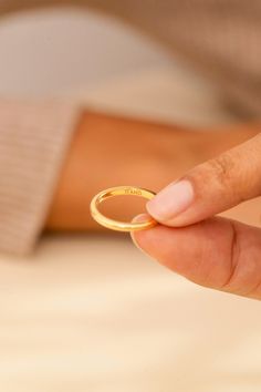 a person holding a gold ring in their hand