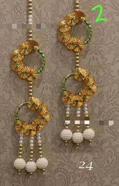 two gold and green beaded earrings with pearls hanging from the side, on a wall